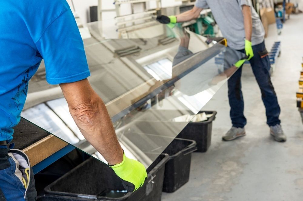 Two Men Are Carrying A Large Piece Of Glass In A Factory — Northern Glazing Glass & Aluminium In Smithfield, QLD