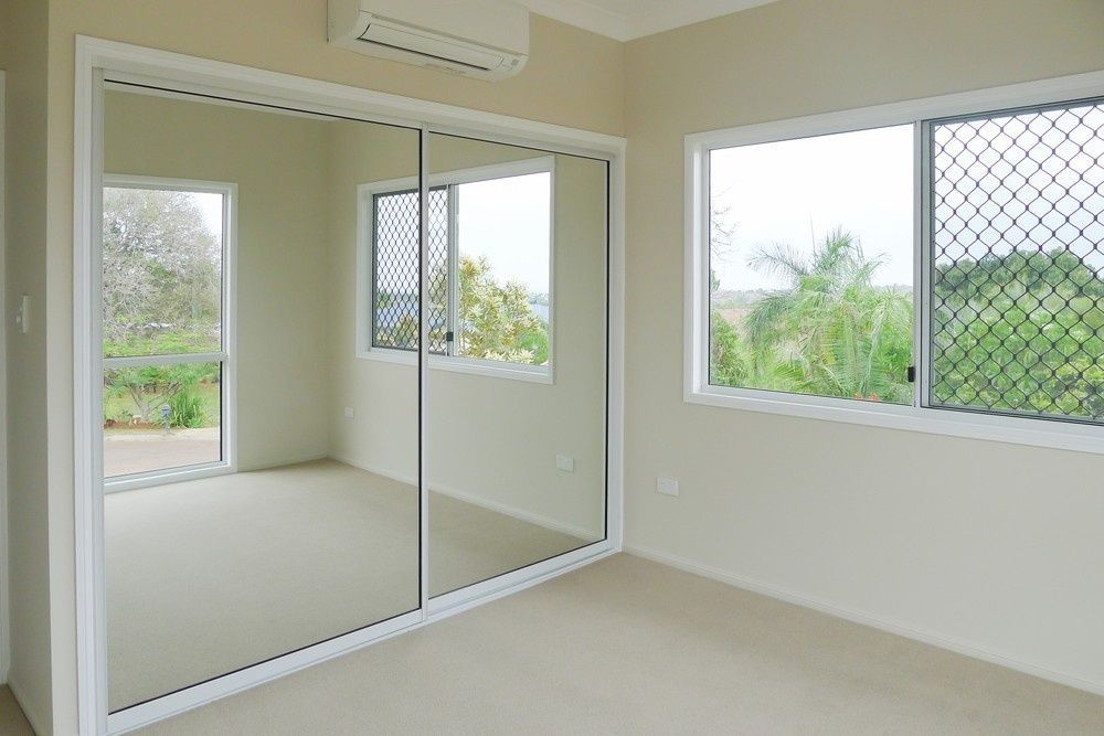 An Empty Bedroom With Sliding Glass Doors And Two Windows — Northern Glazing Glass & Aluminium In Smithfield, QLD