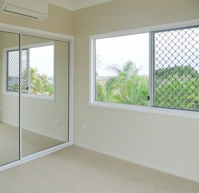 An Empty Bedroom With Sliding Glass Doors And Two Windows — Northern Glazing Glass & Aluminium In Smithfield, QLD