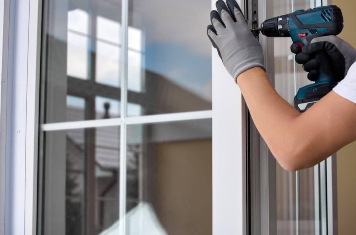 A Person Is Installing A Window With A Drill — Northern Glazing Glass & Aluminium In Smithfield, QLD