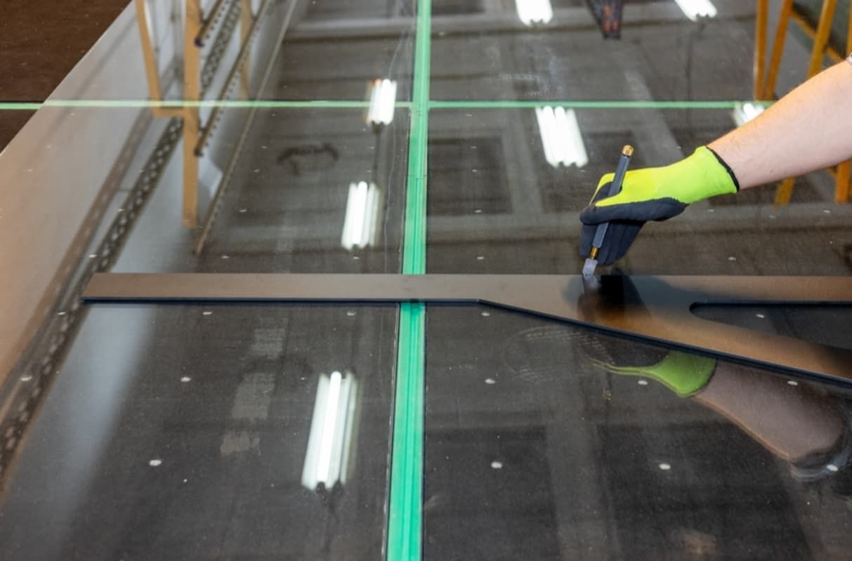 A Person Is Cutting A Piece Of Glass With A Pair Of Scissor — Northern Glazing Glass & Aluminium In Smithfield, QLD
