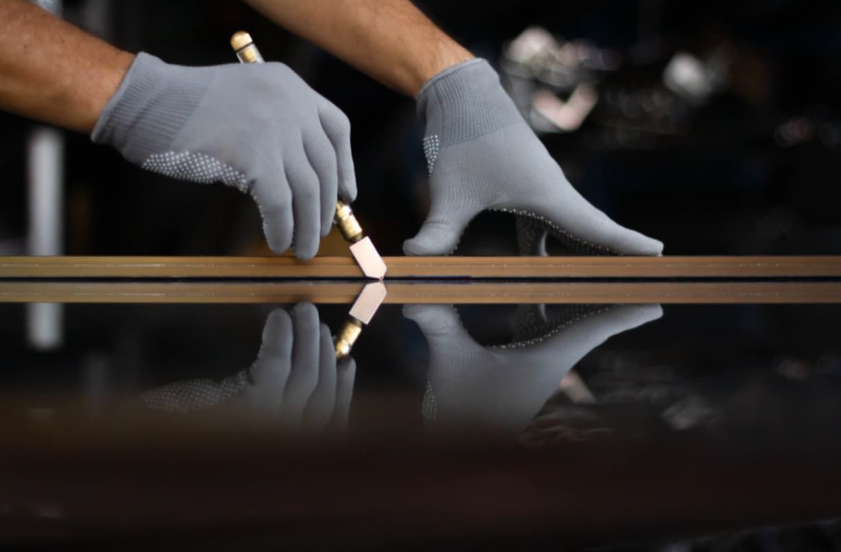 A Person Is Cutting A Piece Of Glass With A Glass Cutter — Northern Glazing Glass & Aluminium In Port Douglas, QLD