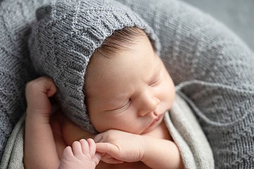 chlafendes Neugeborenes mit Strickmütze – natürliches Newborn Shooting München