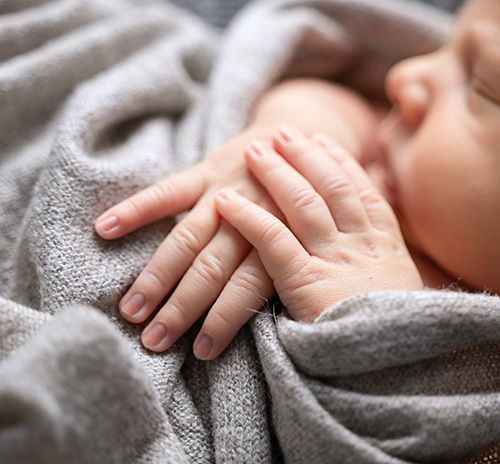 Detailaufnahme Babyhände und Gesicht – emotionale Neugeborenenfotografie zu Hause