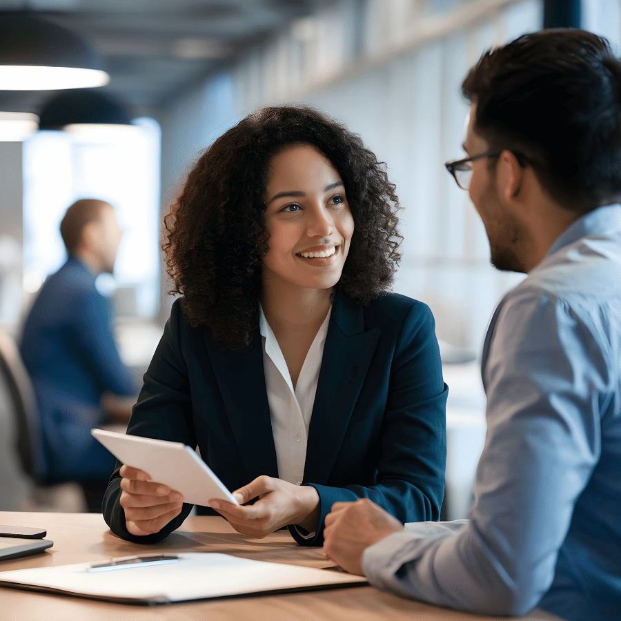 Two coworkers smiling and talking over documents in a bright office