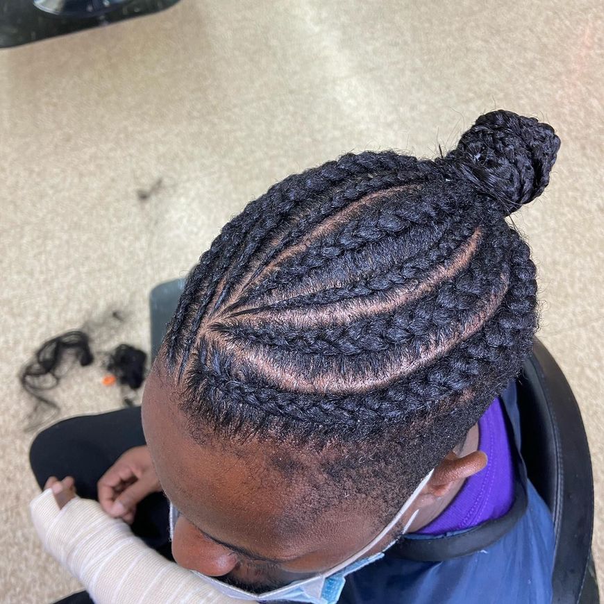 Person with braided hairstyle; some braids are in a top bun.