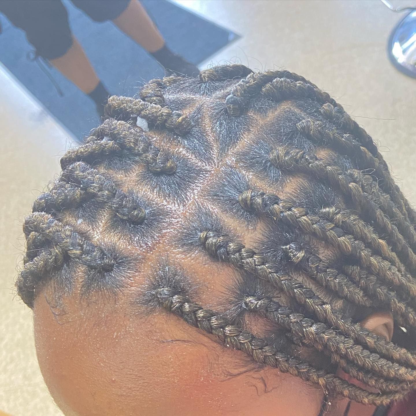 Close-up of a person's head with neatly braided hair, creating a geometric pattern on the scalp.
