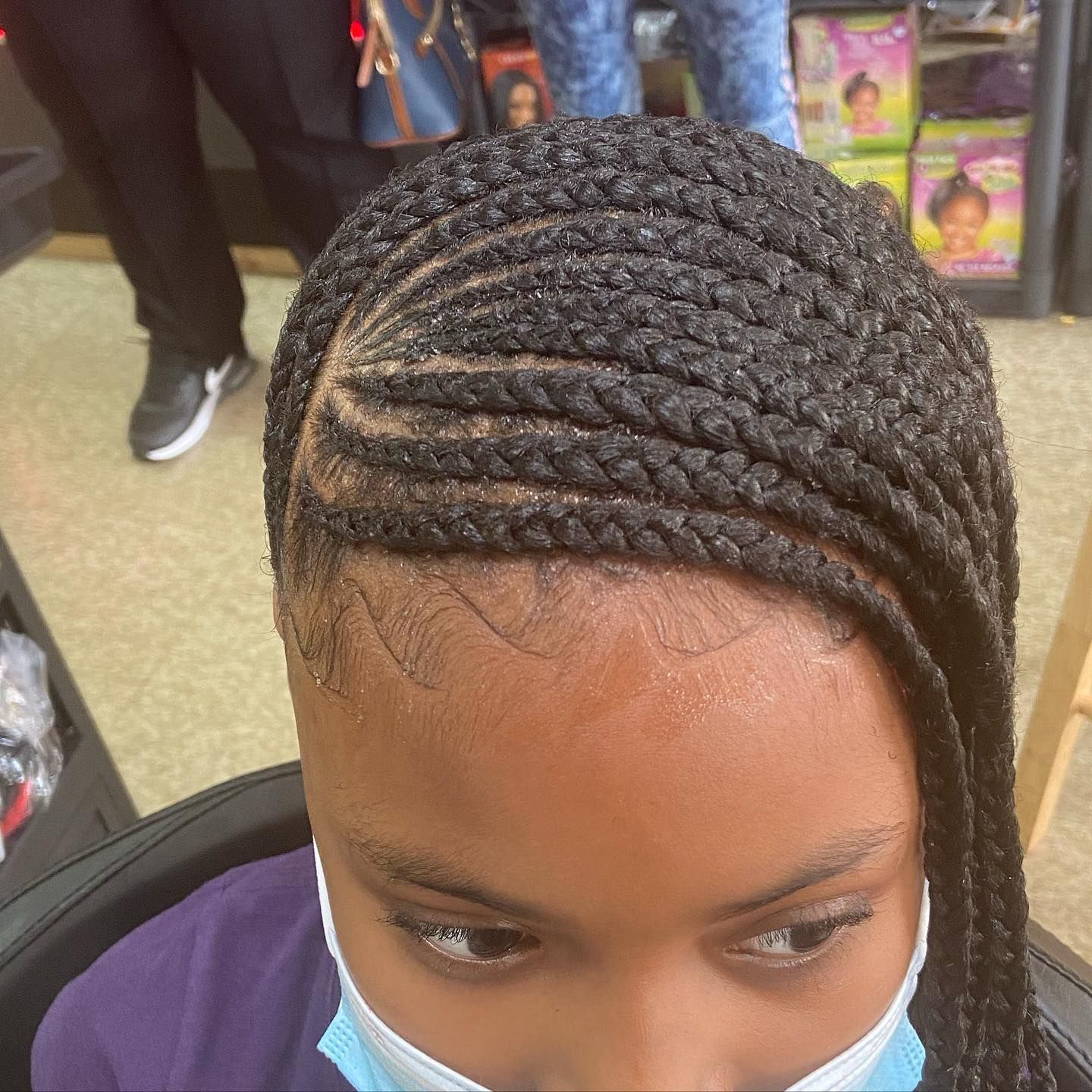 Braided hairstyle with angled part, woman wearing face mask.