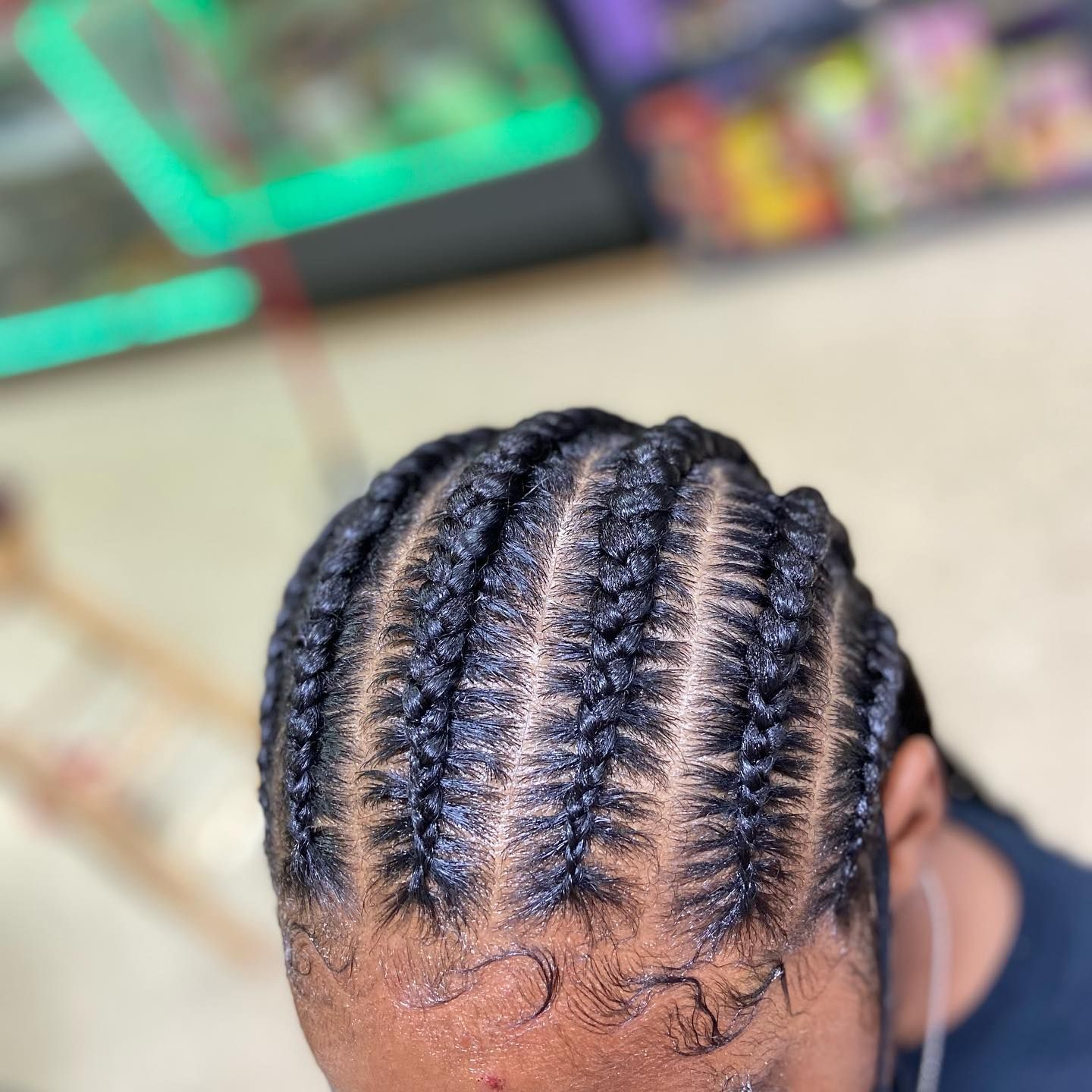 Close-up of cornrow braids styled on a person's head. Braids are dark, sleek, and closely woven.