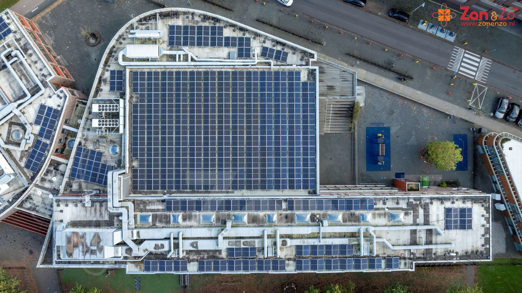 Een luchtfoto van een groot gebouw met zonnepanelen op het dak.