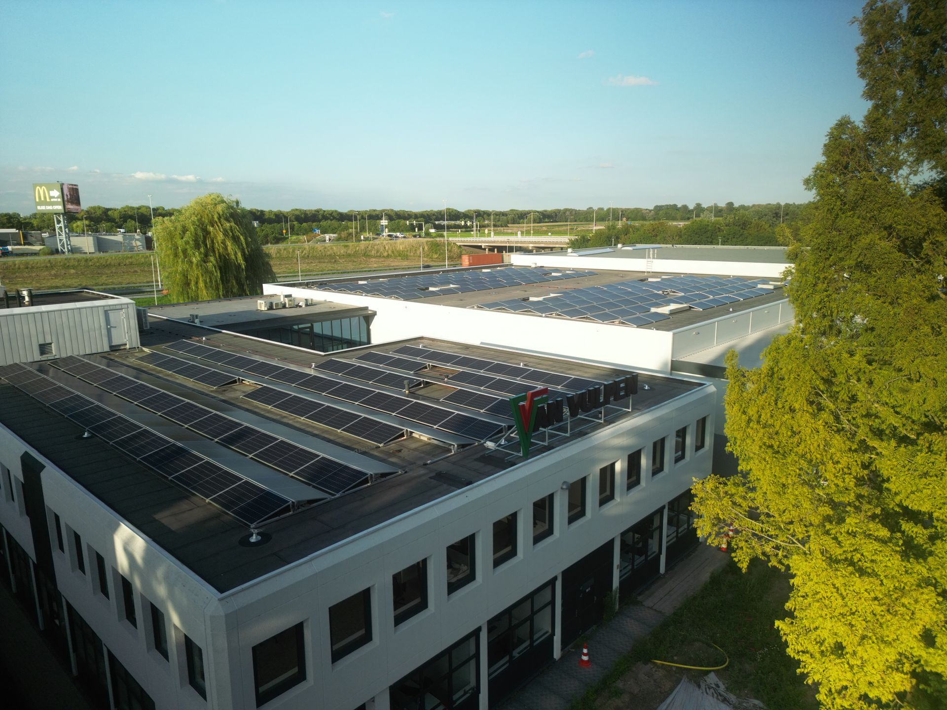 Een luchtfoto van een groot gebouw met zonnepanelen op het dak.