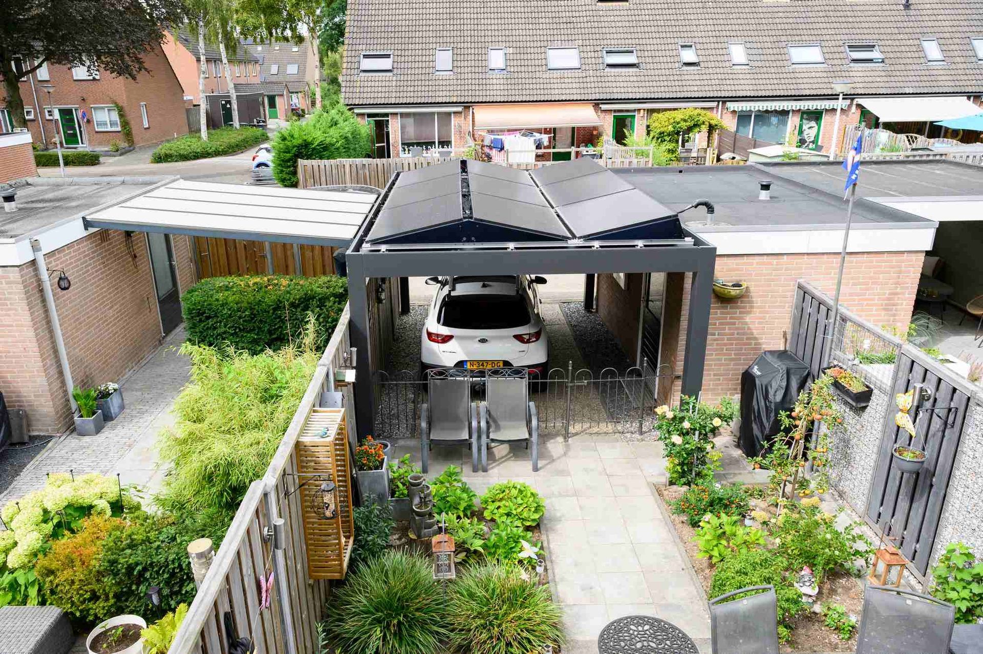 Een auto staat geparkeerd onder een afdak in de achtertuin van een huis.