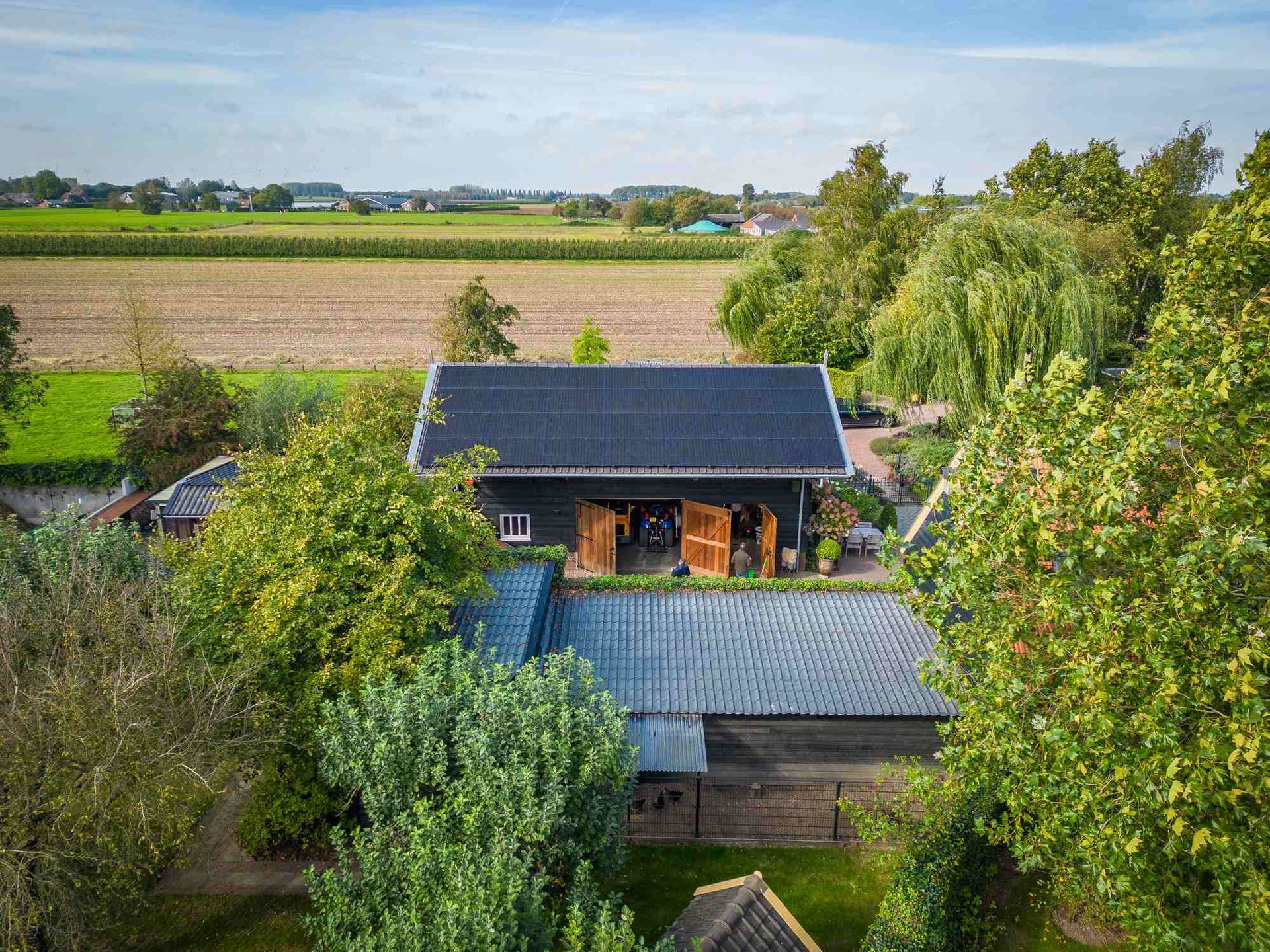 Een luchtfoto van een huis omgeven door bomen en velden.