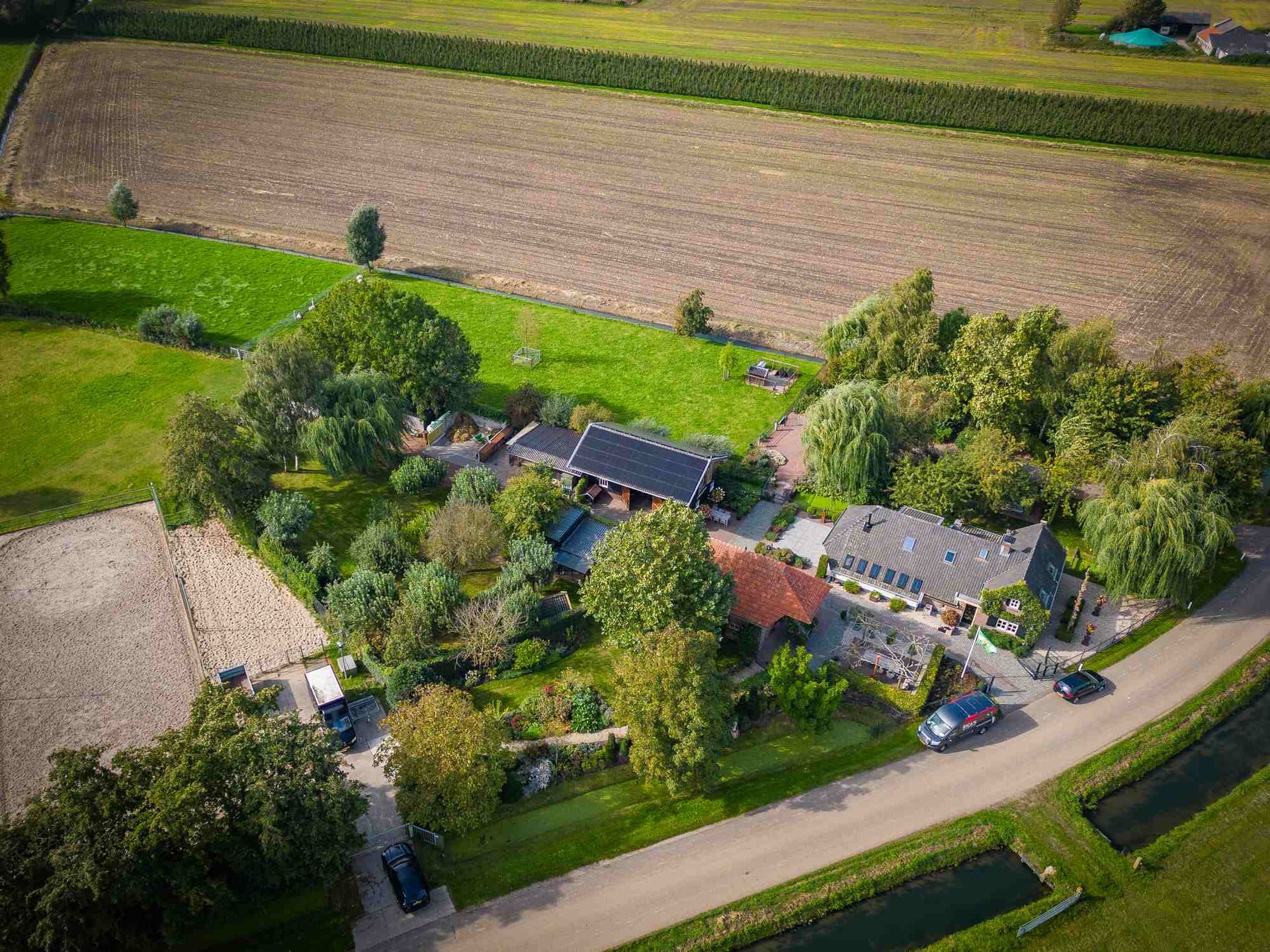 Een luchtfoto van een boerderij omgeven door velden en bomen.