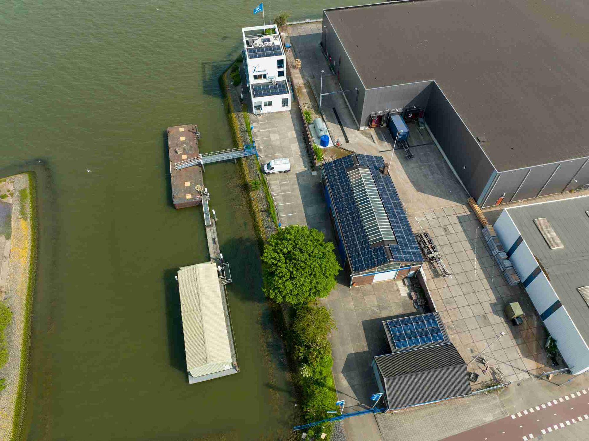 Een luchtfoto van een gebouw naast een waterpartij.