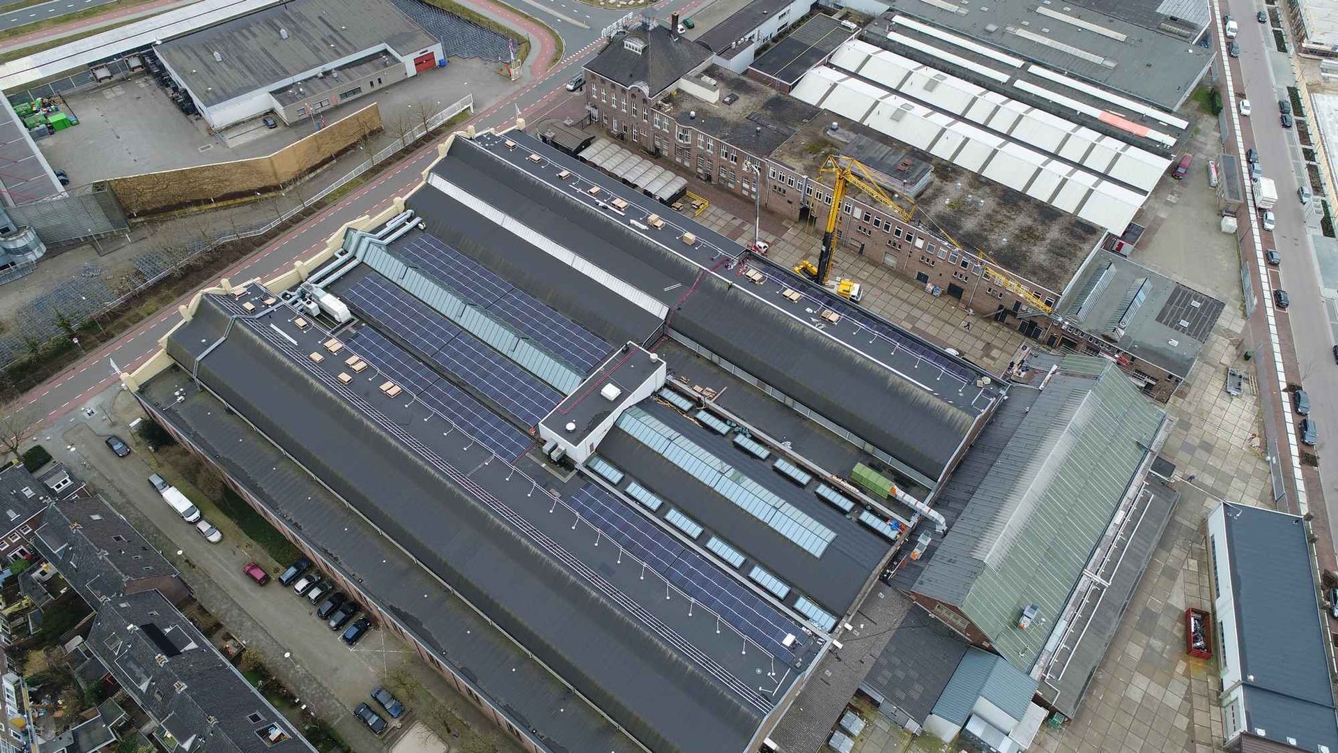 Een luchtfoto van een fabriek met zonnepanelen op het dak.