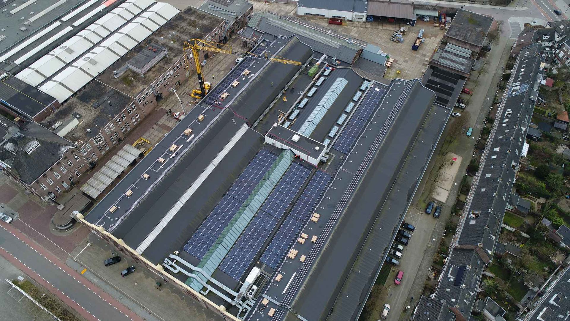 Een luchtfoto van een groot gebouw met zonnepanelen op het dak.