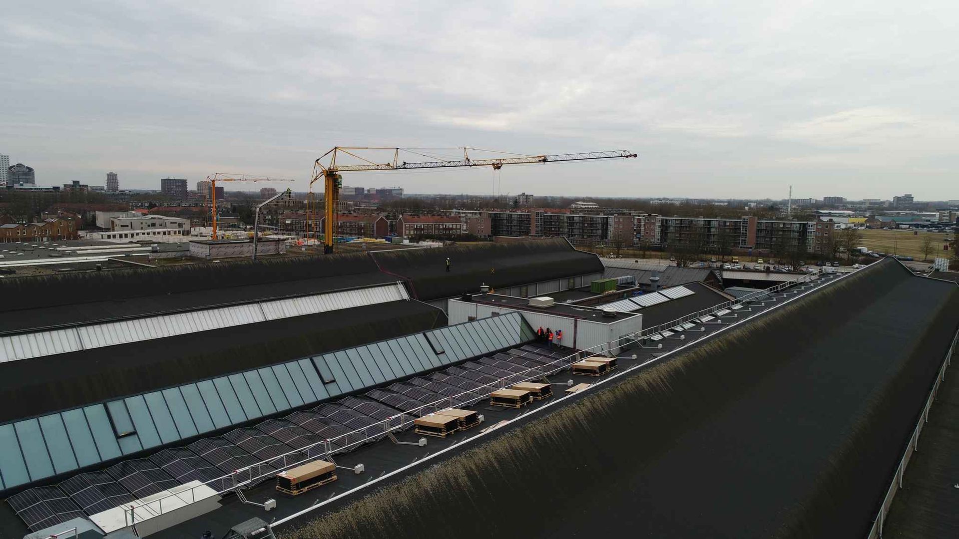 Een luchtfoto van een groot gebouw met daarop een kraan.