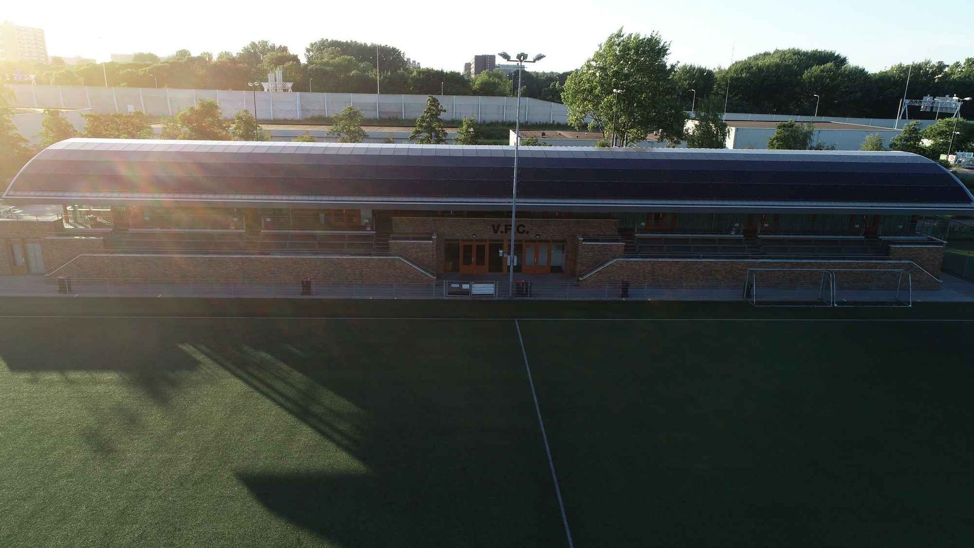 Een luchtfoto van een voetbalveld met een gebouw op de achtergrond.