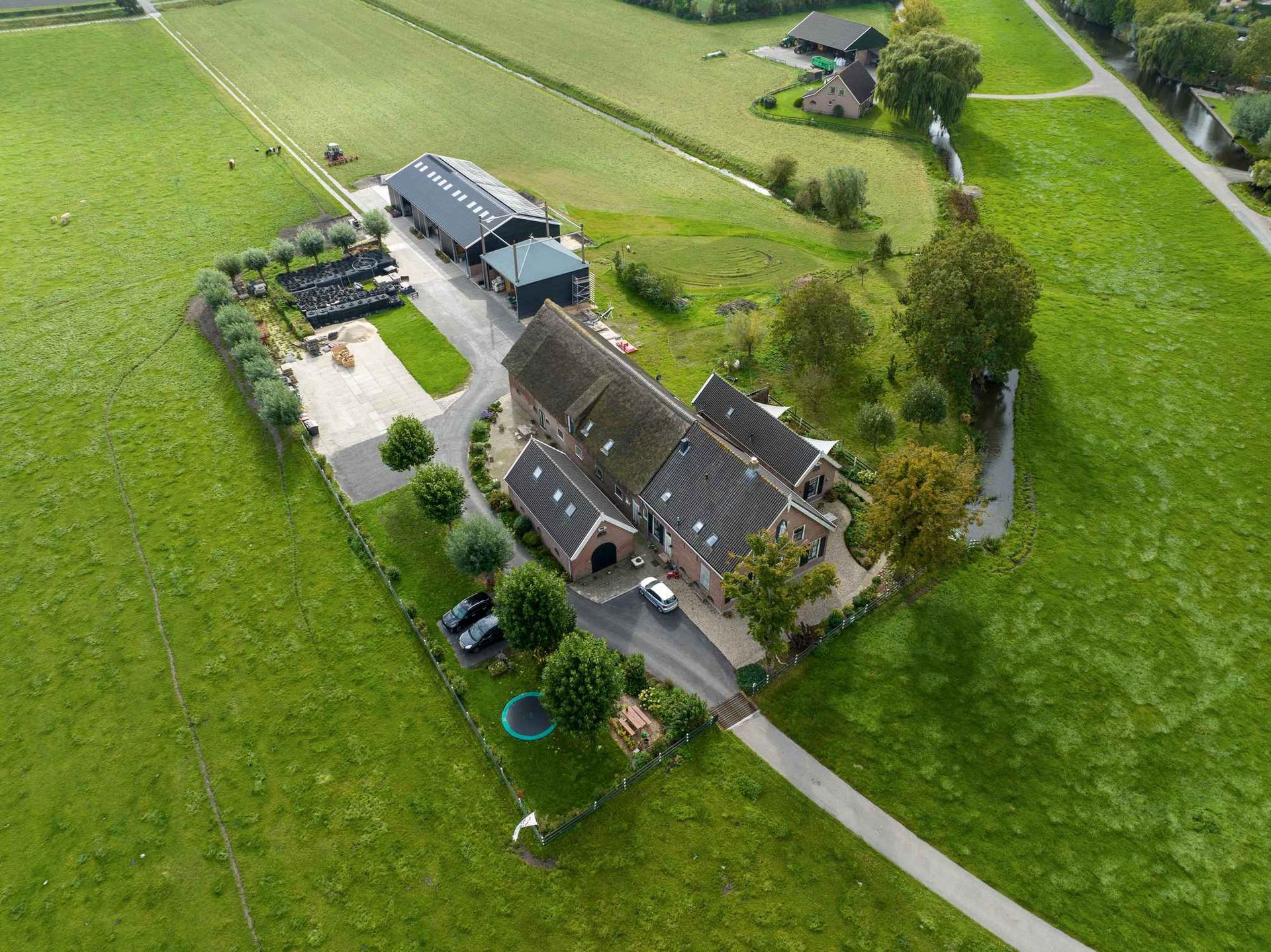 Een luchtfoto van een boerderij met een grote schuur in het midden van een grasveld.