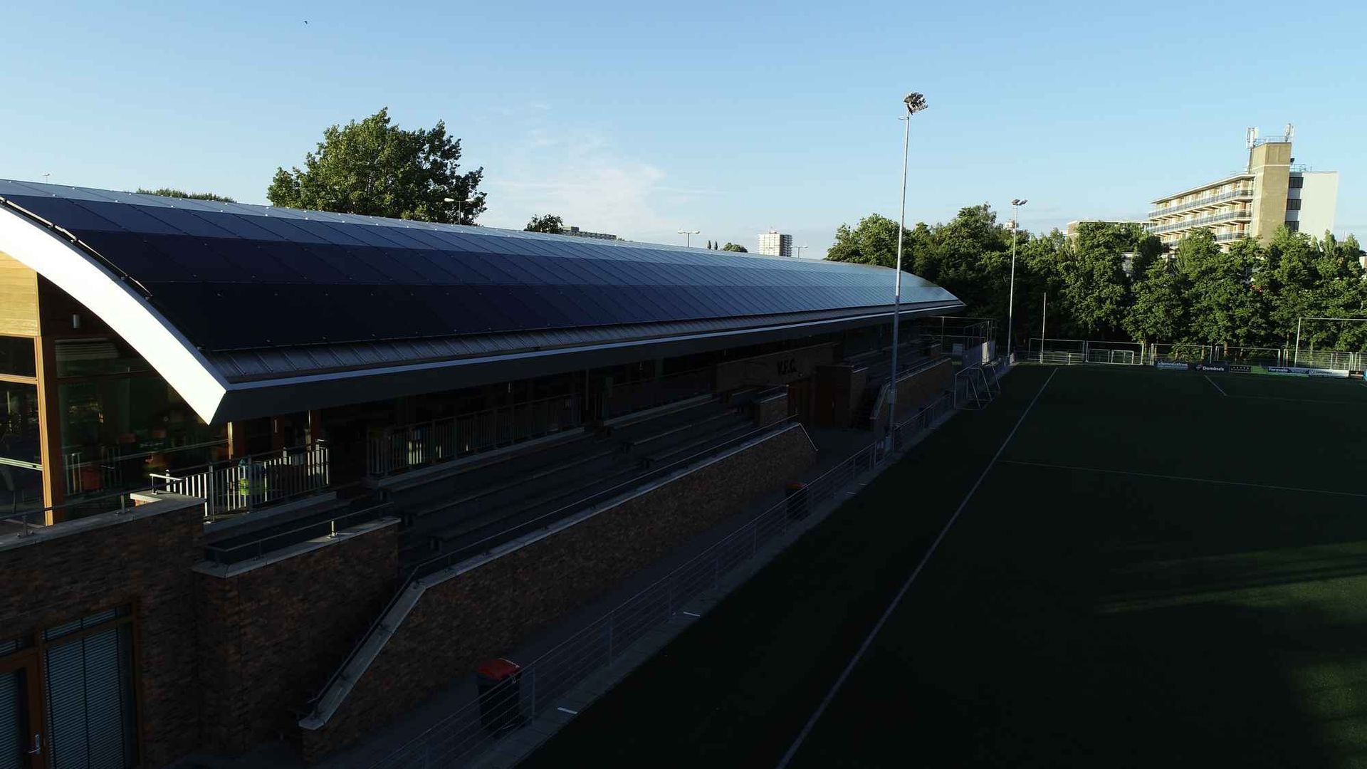 Een luchtfoto van een voetbalveld met een gebouw op de achtergrond