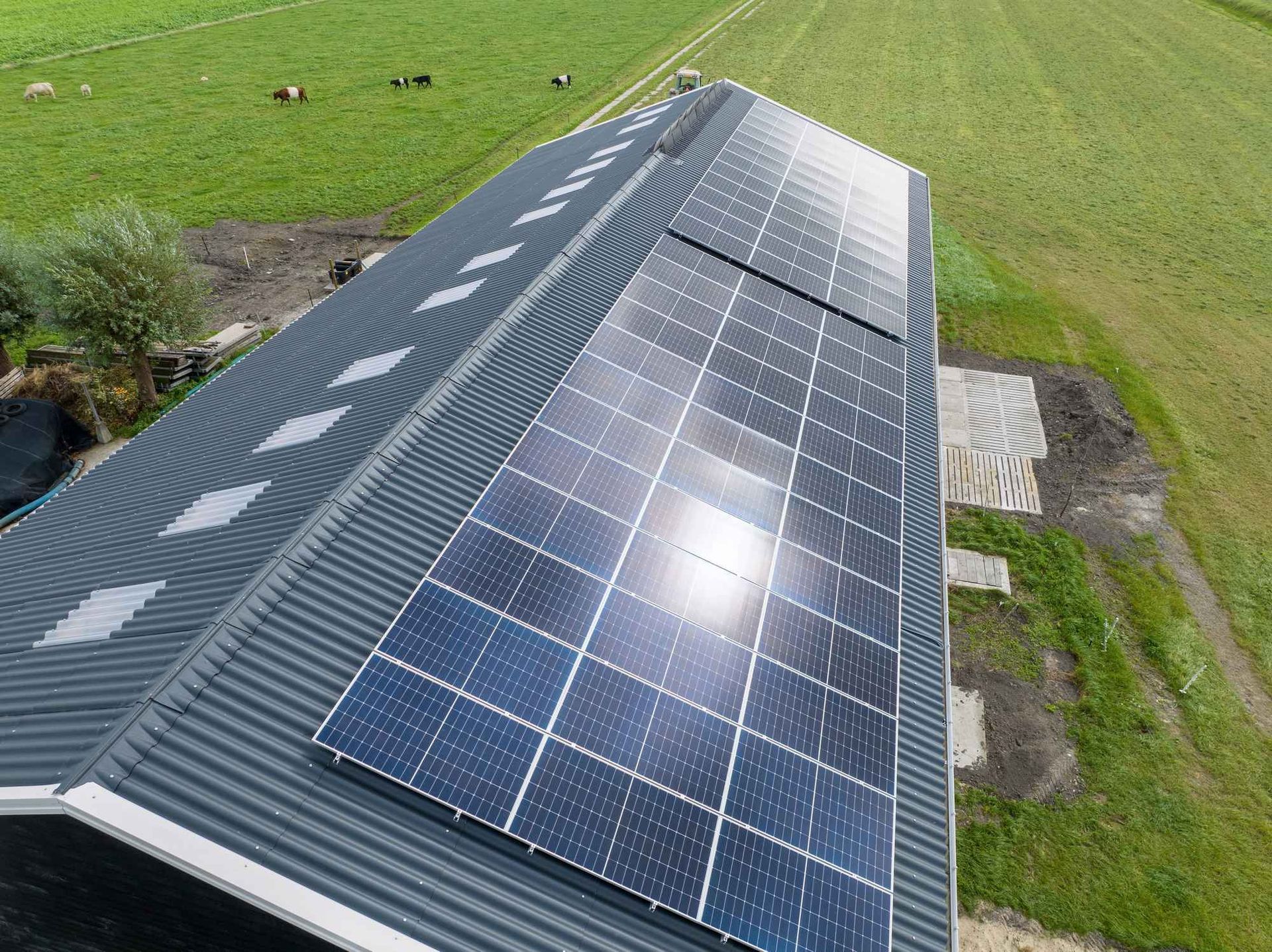 Een luchtfoto van een schuur met zonnepanelen op het dak.