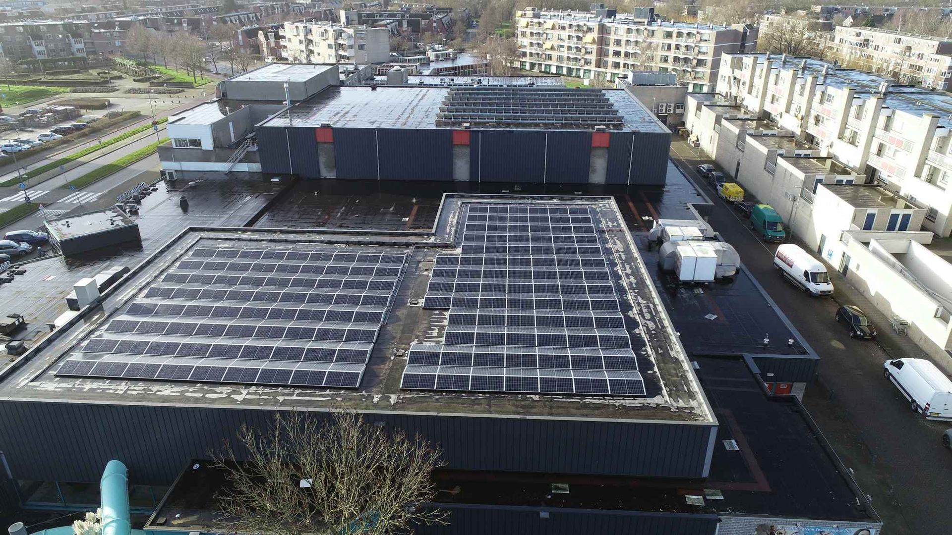 Een luchtfoto van een groot gebouw met zonnepanelen op het dak.