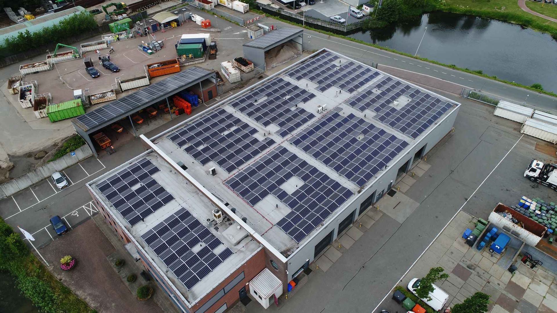 Een luchtfoto van een groot gebouw met veel zonnepanelen op het dak.