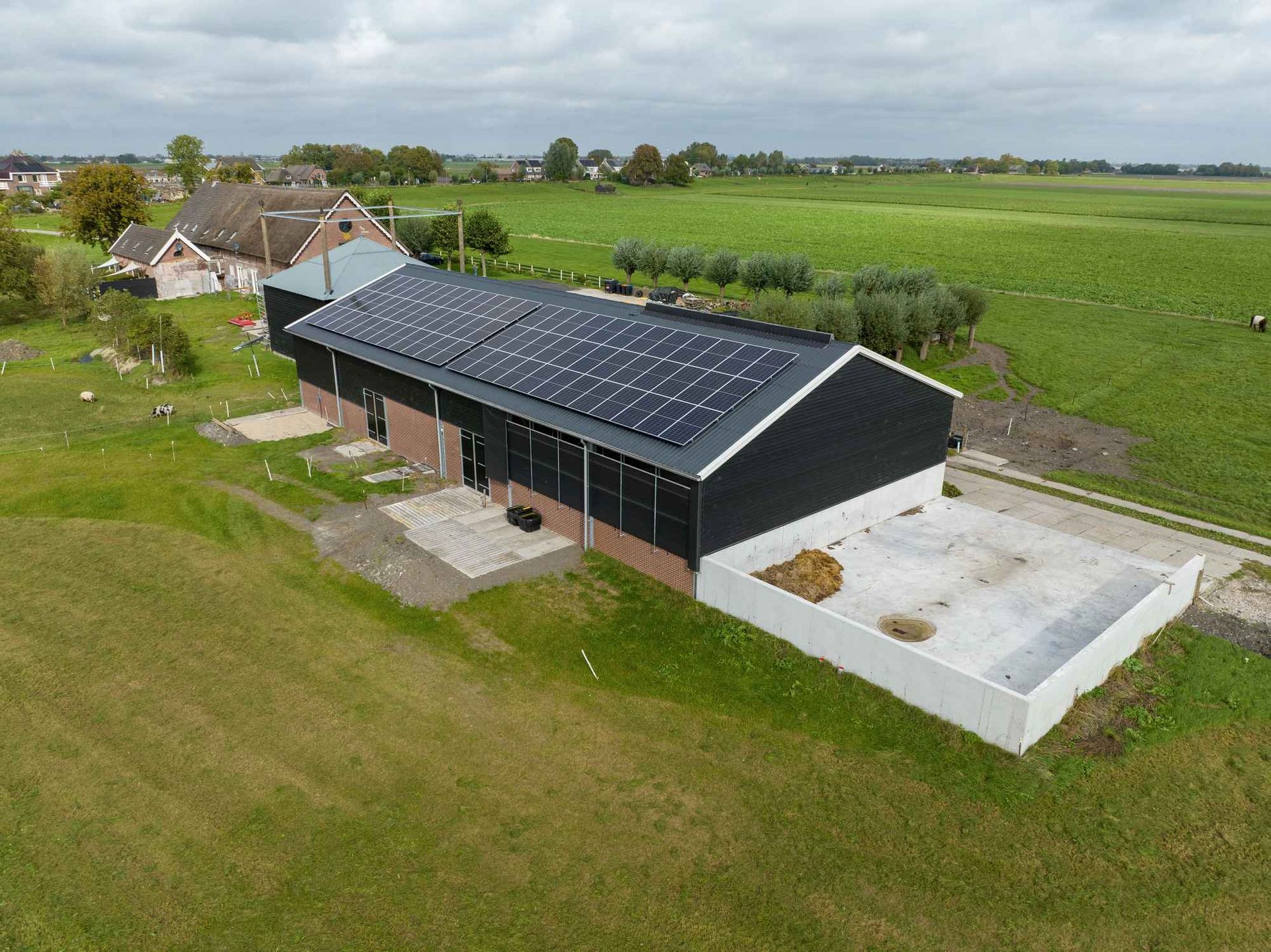 Een luchtfoto van een schuur met zonnepanelen op het dak.