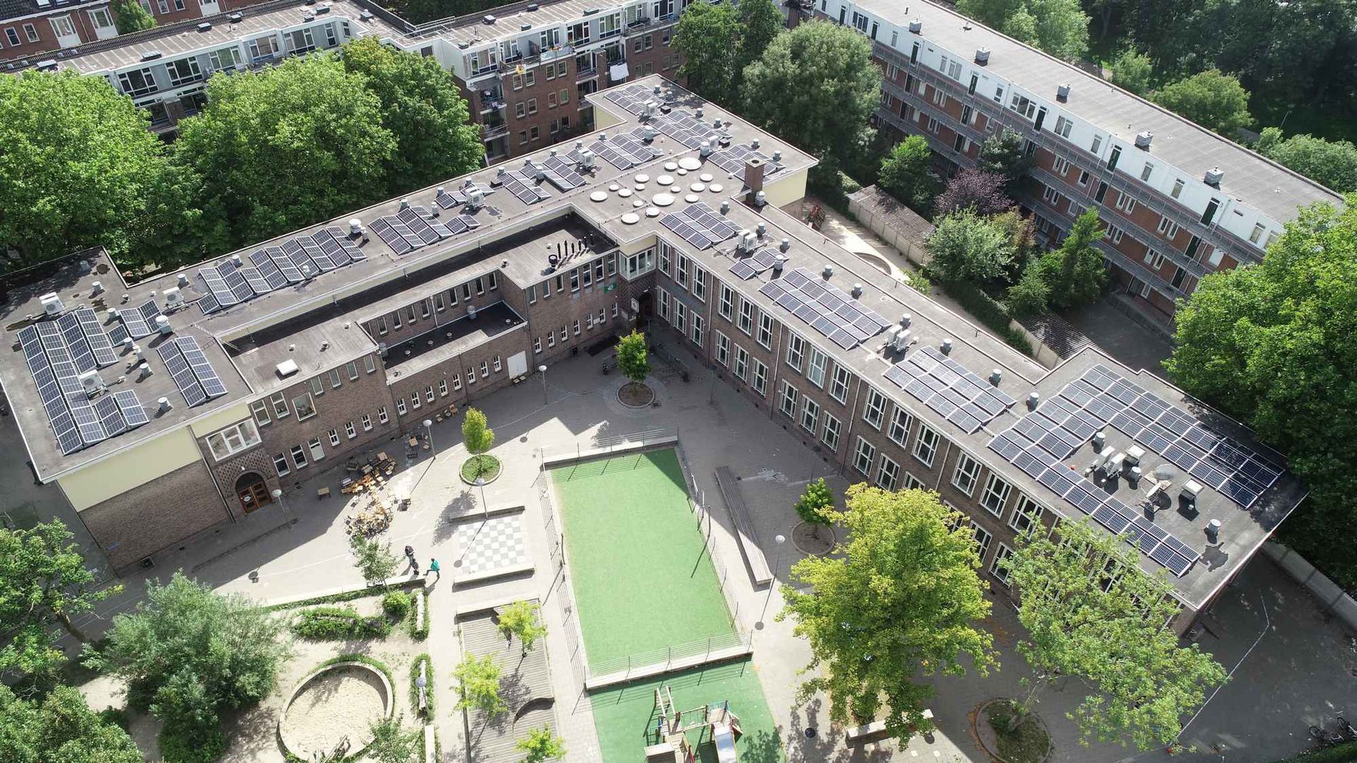 Een luchtfoto van een groot gebouw met zonnepanelen op het dak.