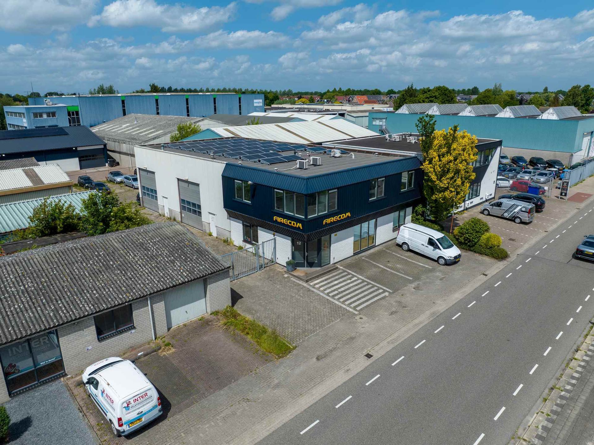 Een luchtfoto van een gebouw met veel auto's ervoor geparkeerd.