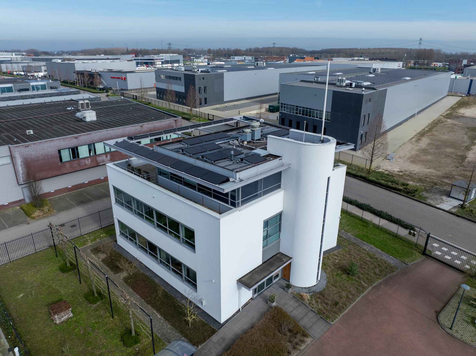 Een luchtfoto van een groot wit gebouw met zonnepanelen op het dak.