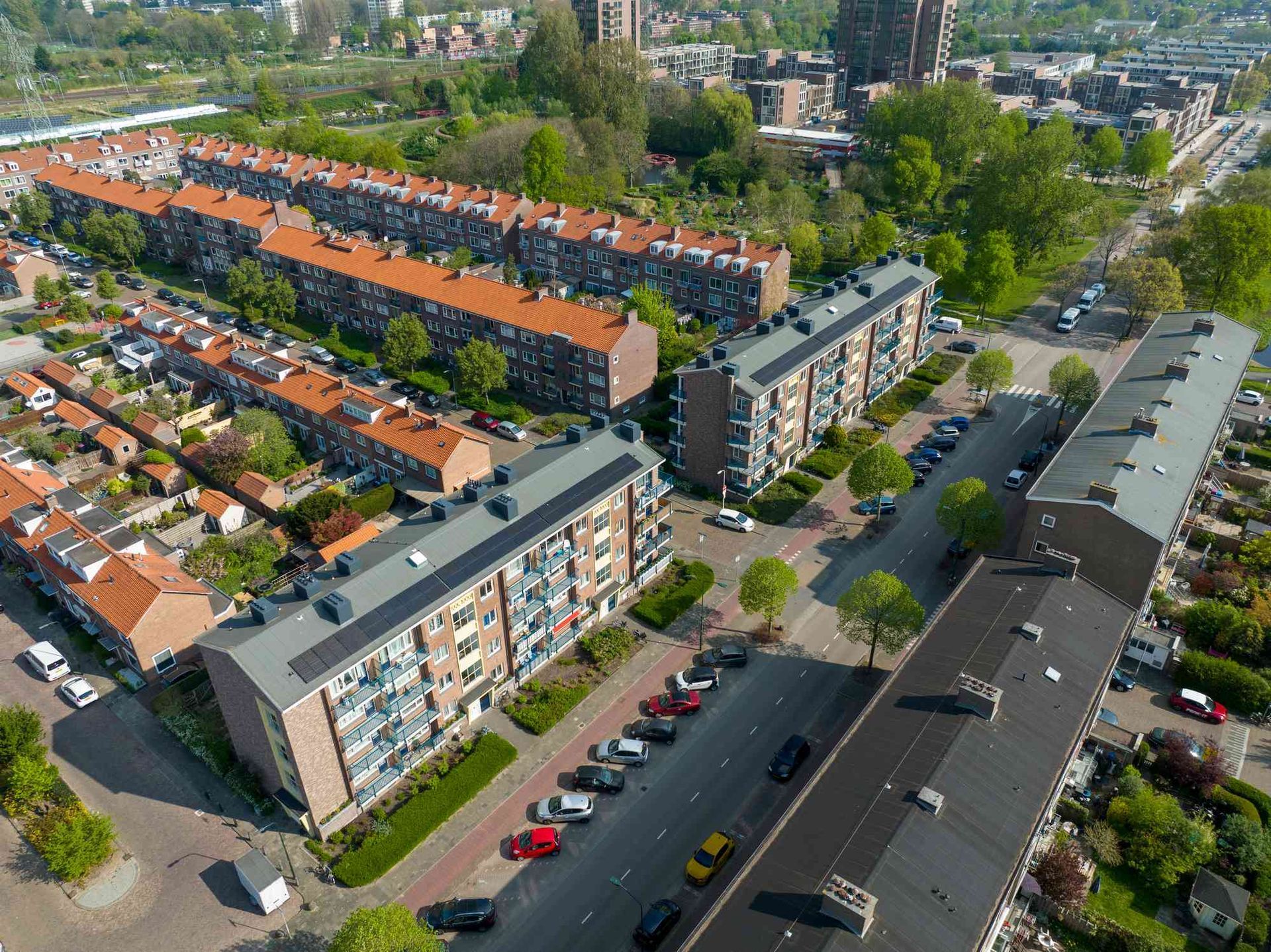 Een luchtfoto van een woonwijk met veel gebouwen en auto's die ervoor geparkeerd staan.
