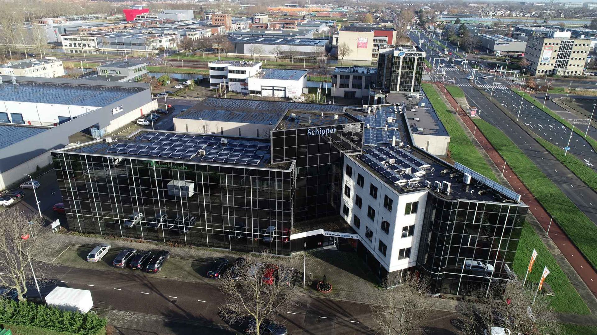 Een luchtfoto van een groot gebouw met zonnepanelen op het dak.