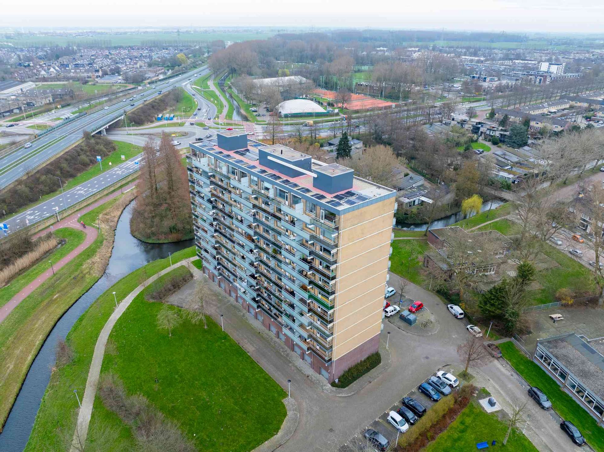 Een luchtfoto van een groot appartementengebouw naast een rivier.