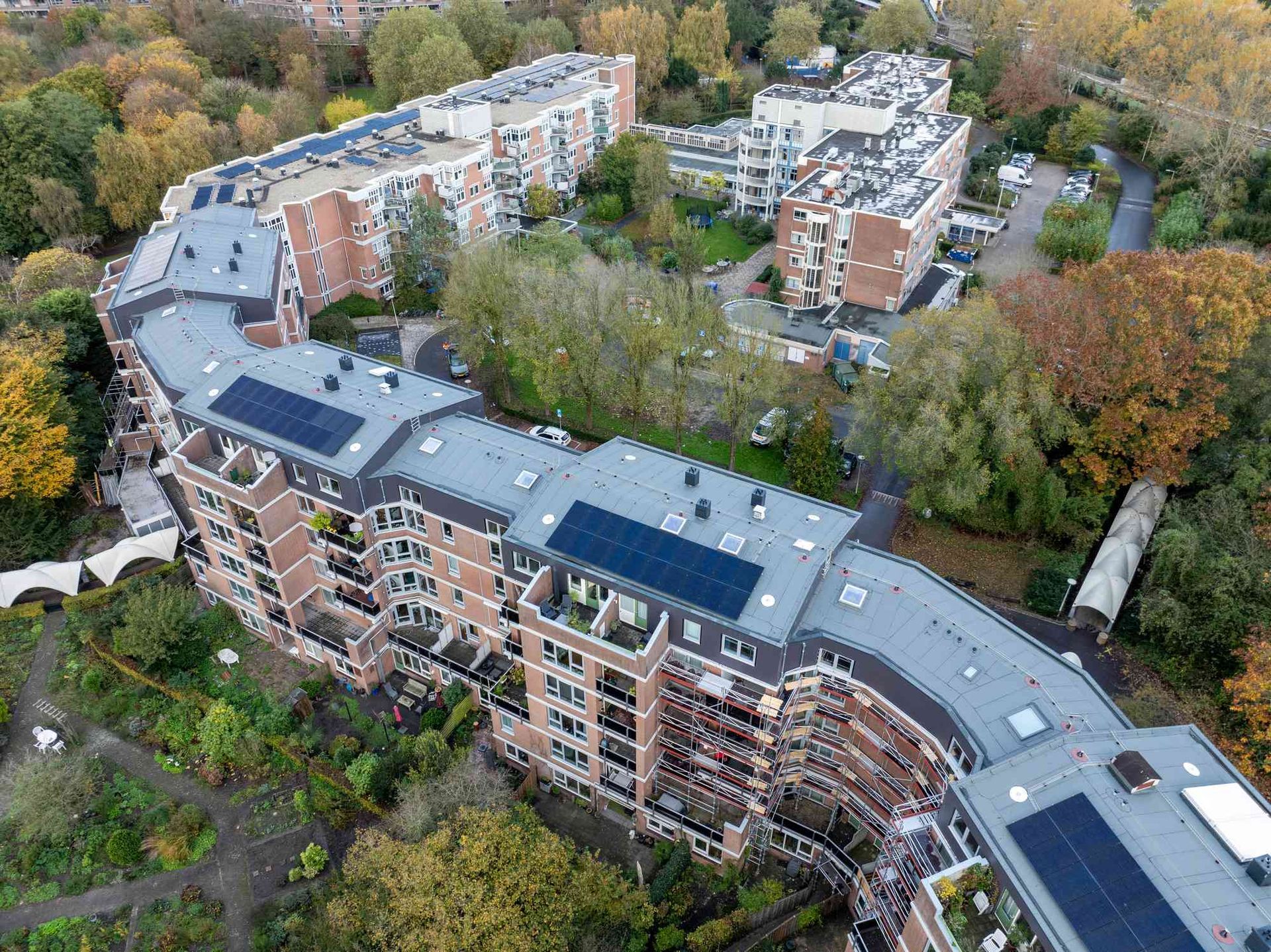 Een luchtfoto van een groot appartementengebouw met zonnepanelen op het dak.