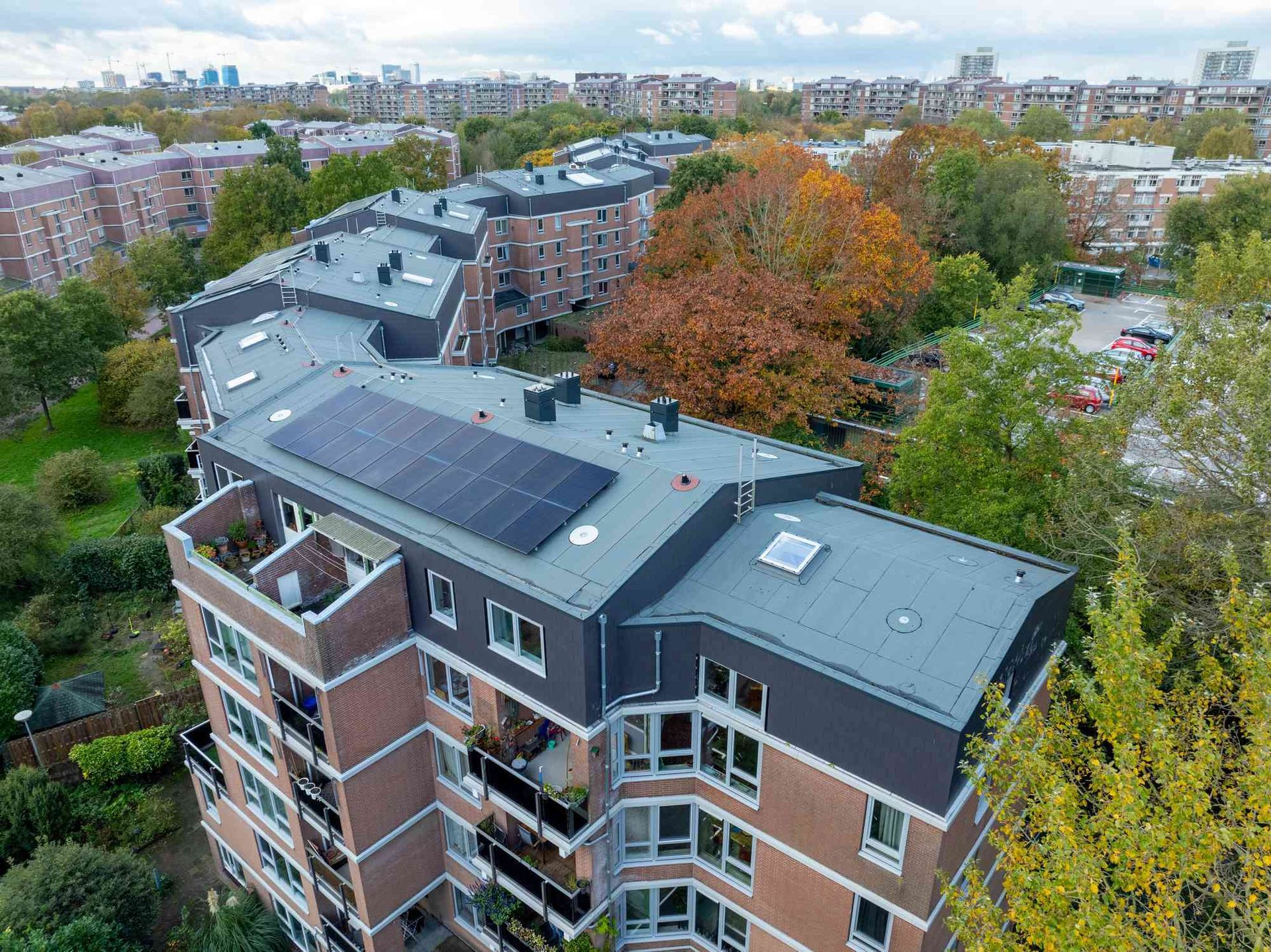 Een luchtfoto van een groot appartementengebouw met zonnepanelen op het dak.