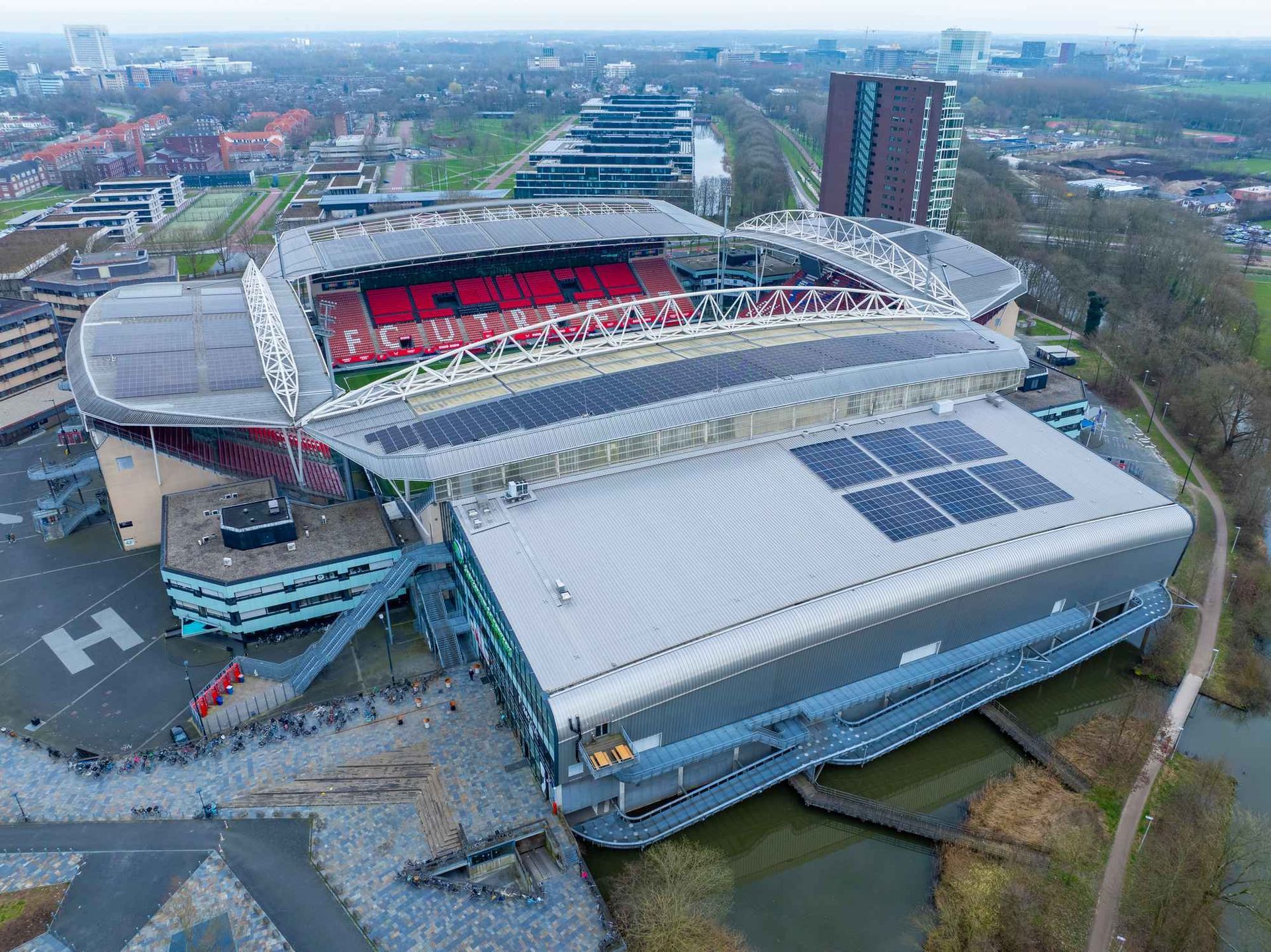 Een luchtfoto van een groot stadion met zonnepanelen op het dak.