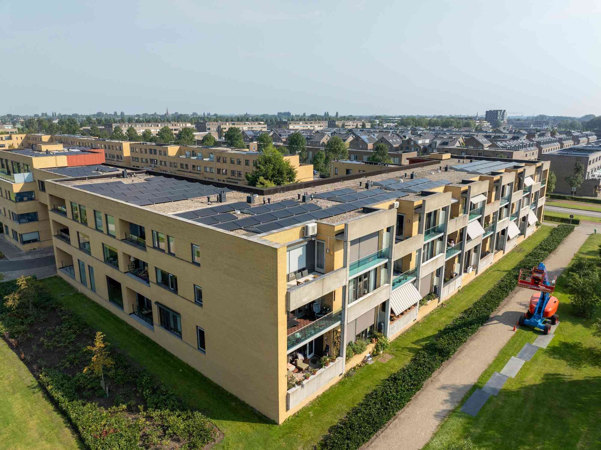 Een luchtfoto van een groot appartementengebouw met zonnepanelen op het dak.
