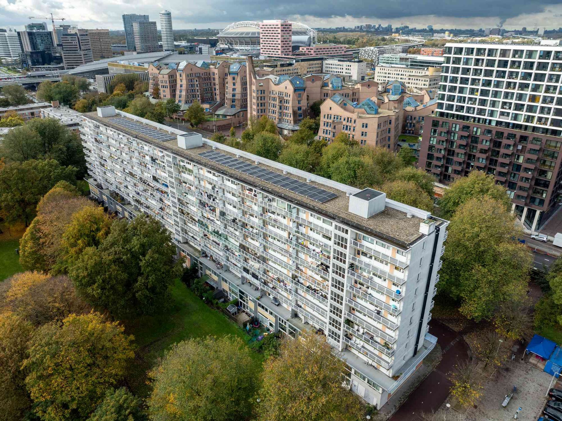 Een luchtfoto van een groot appartementengebouw in een stad, omgeven door bomen.