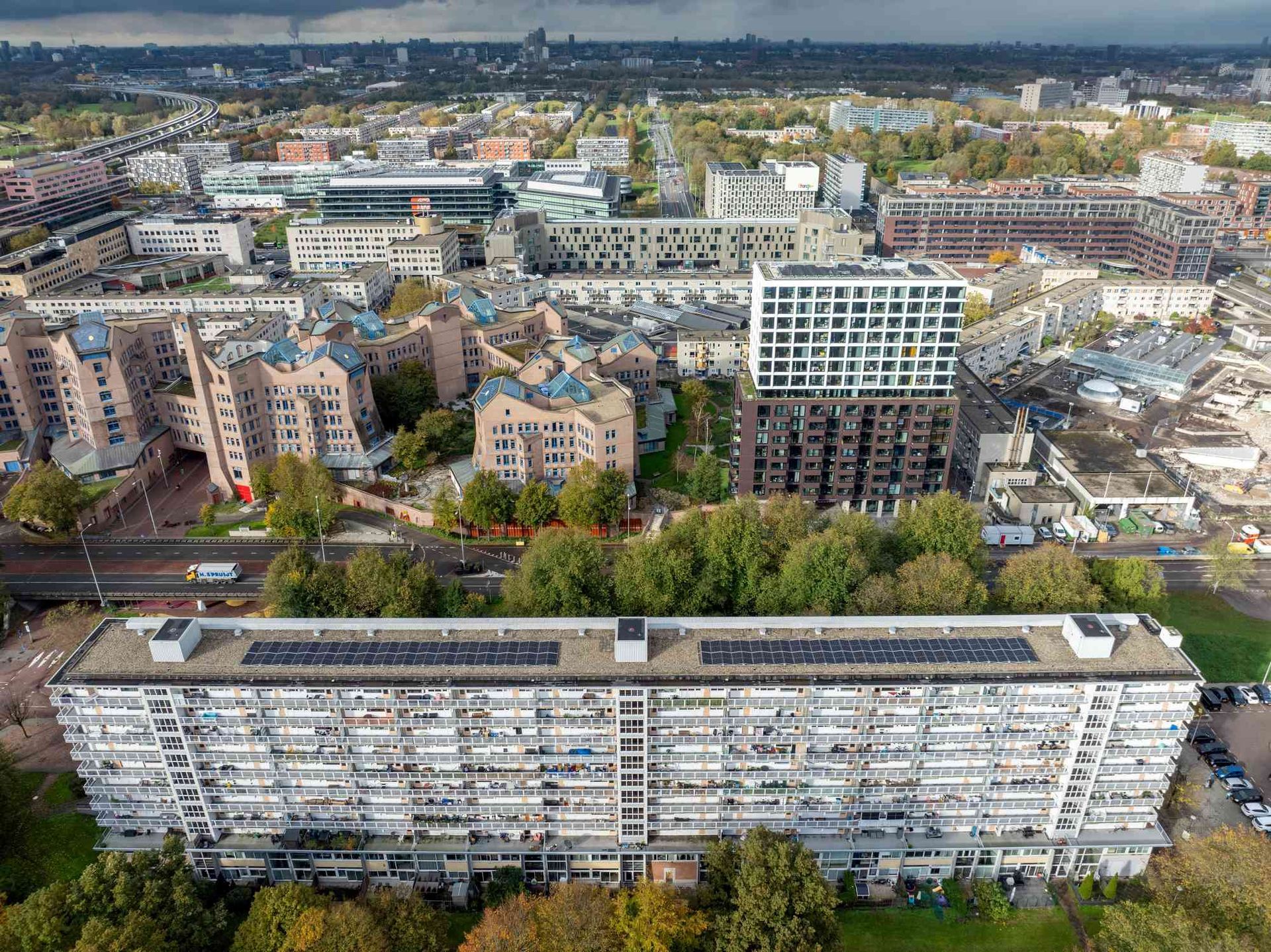 Een luchtfoto van een groot gebouw met zonnepanelen op het dak in een stad.