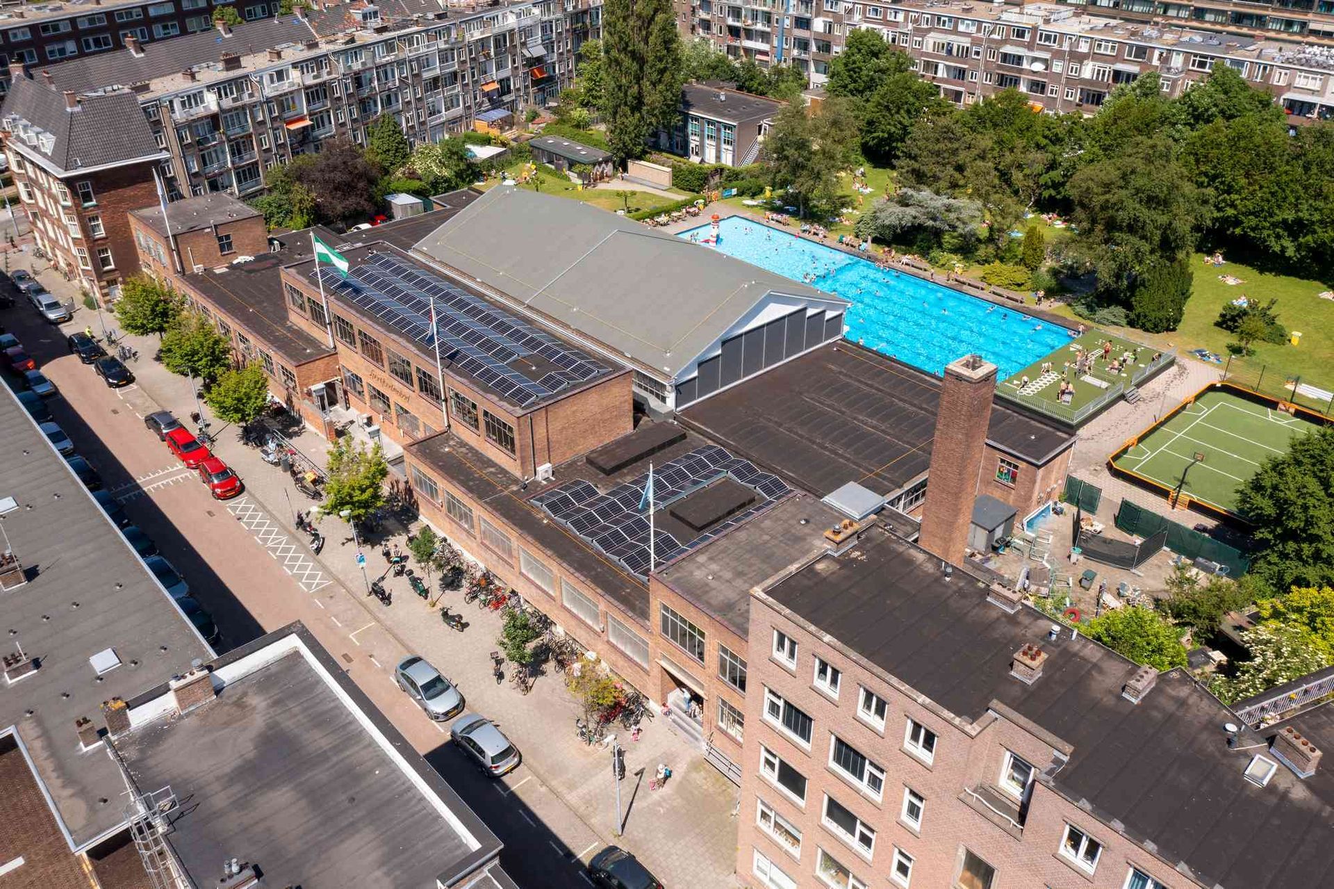 Een luchtfoto van een groot gebouw met een zwembad op de achtergrond.