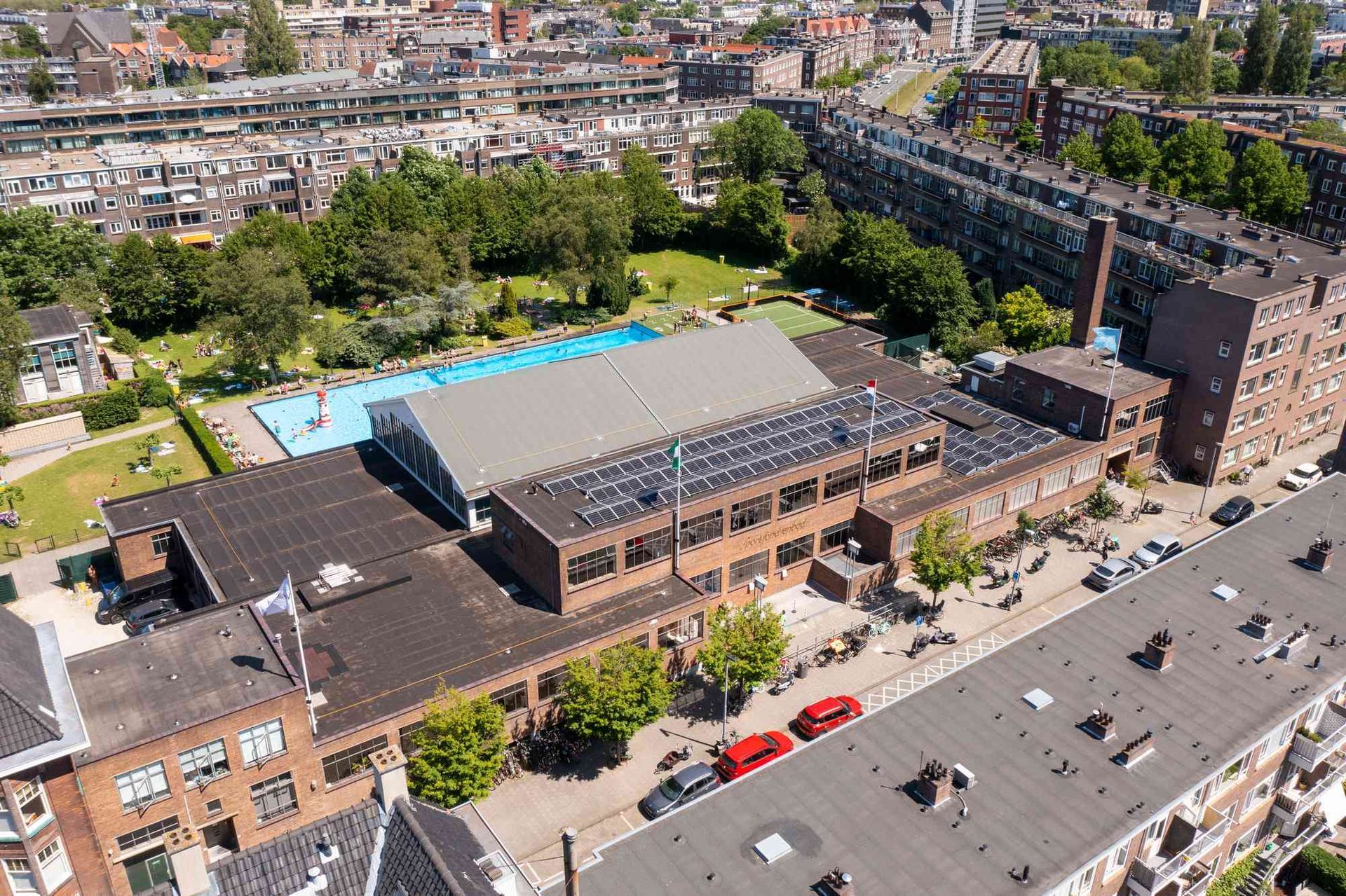 Een luchtfoto van een groot gebouw met een zwembad in het midden van een stad.