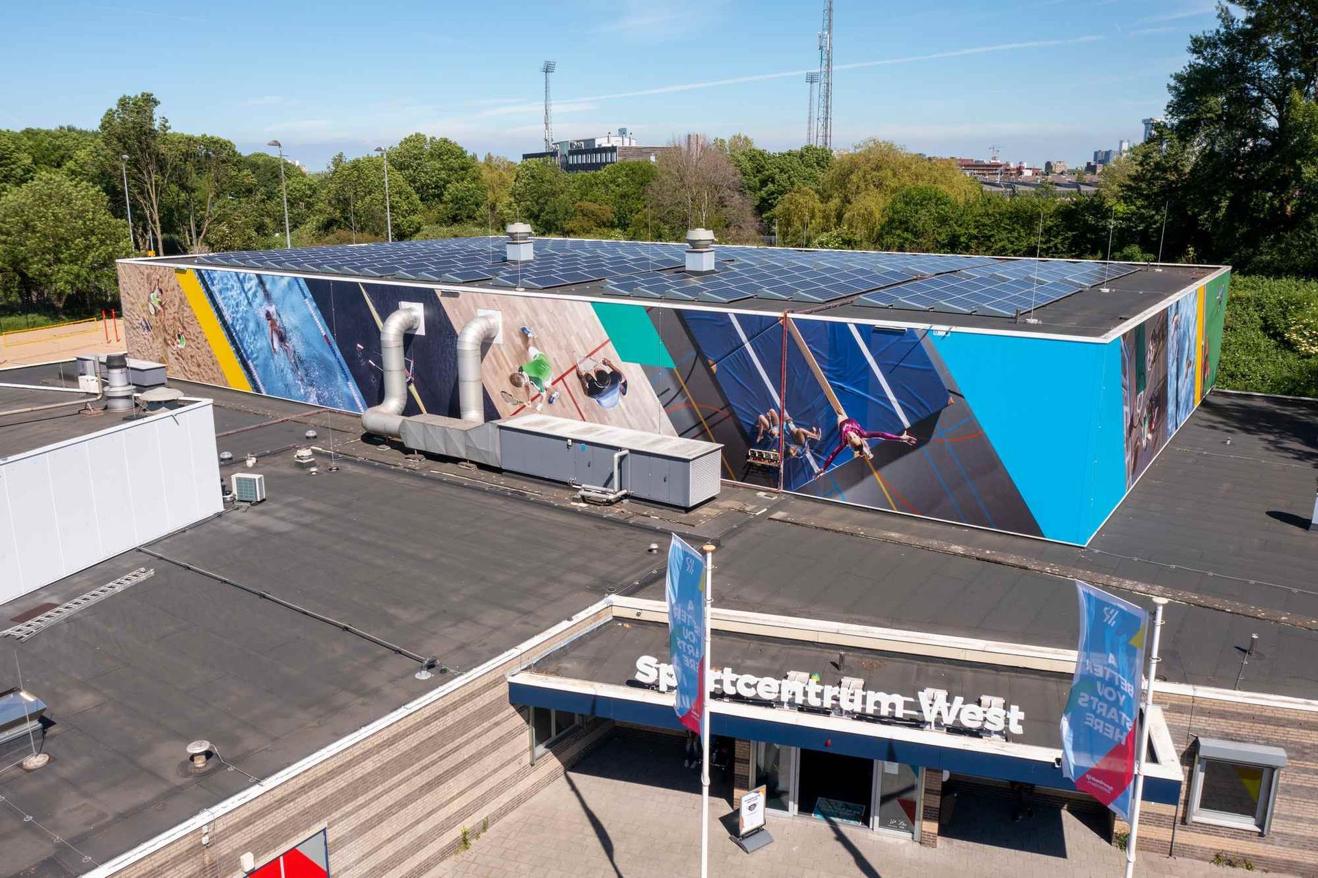 Een luchtfoto van een groot gebouw met veel zonnepanelen op het dak.