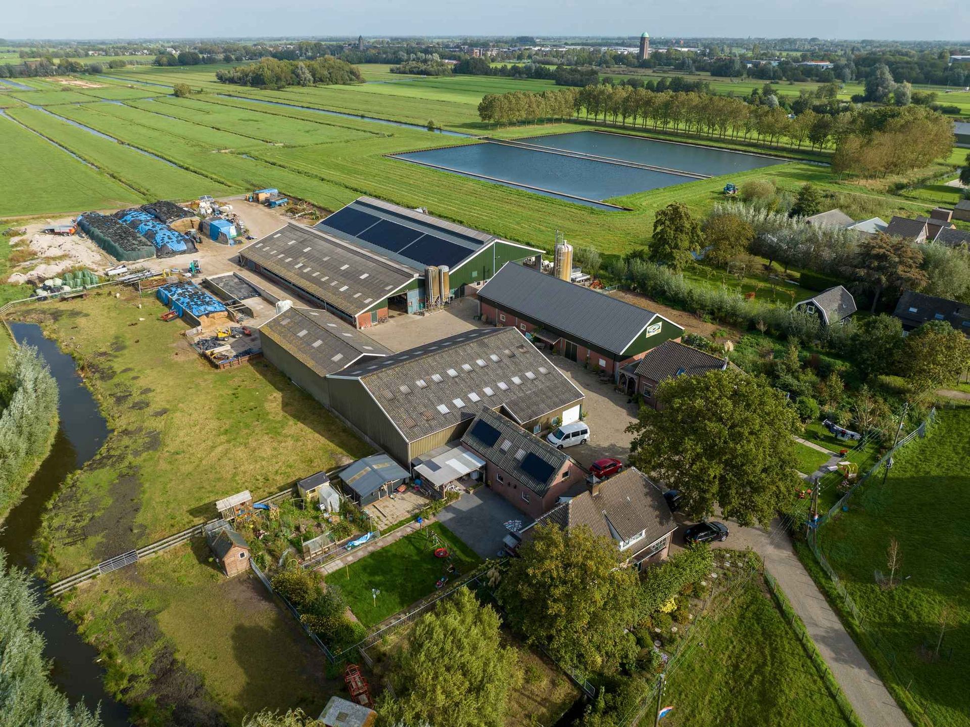 Een luchtfoto van een boerderij met veel gebouwen in het midden van een veld.
