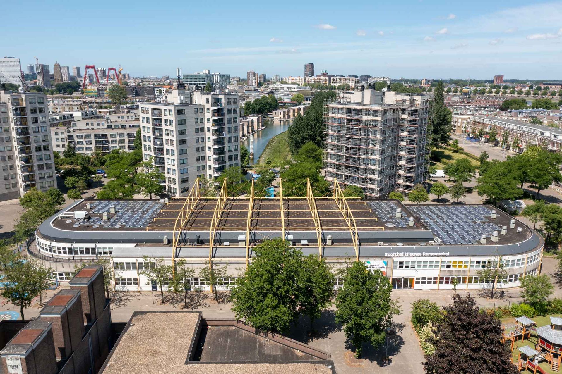 Een luchtfoto van een stad met een groot gebouw met zonnepanelen op het dak.