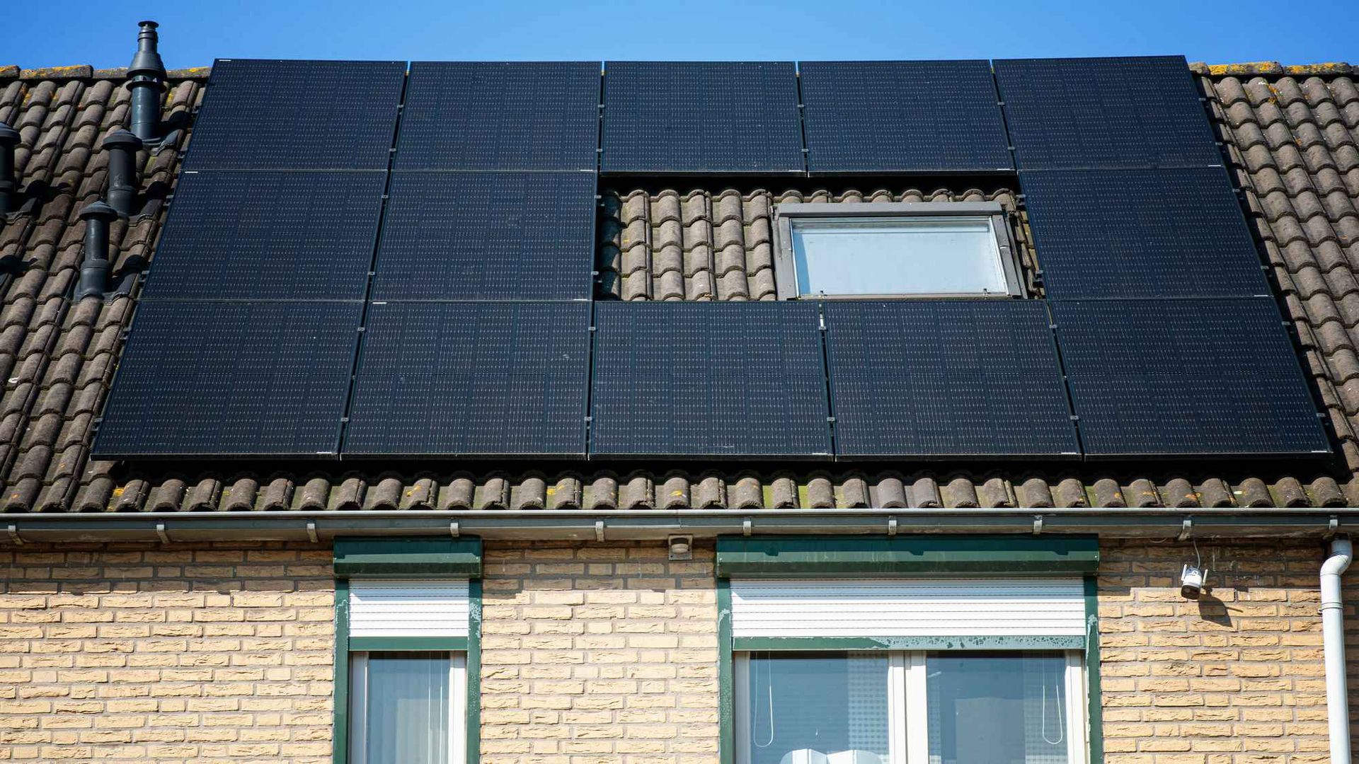 Een bakstenen huis met zonnepanelen op het dak en een raam.