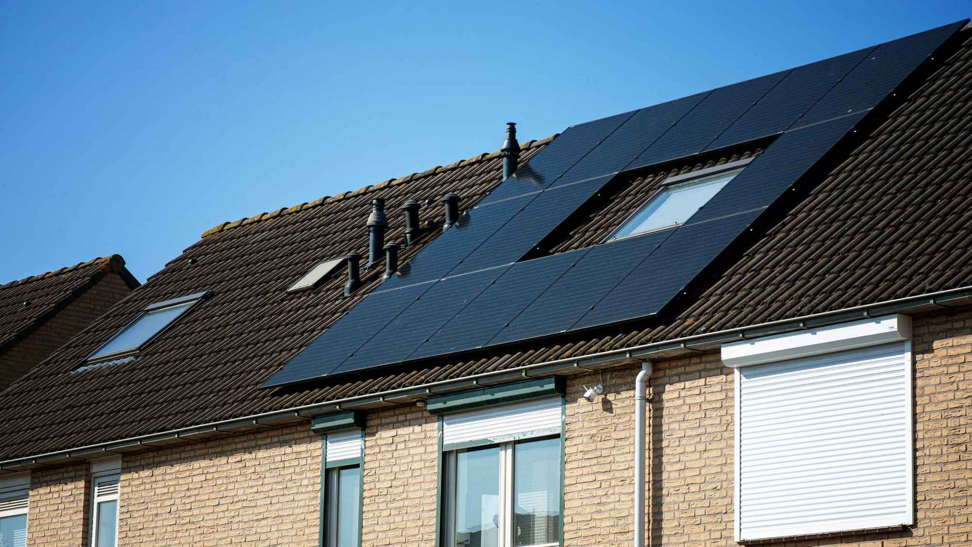Een bakstenen huis met zonnepanelen op het dak.