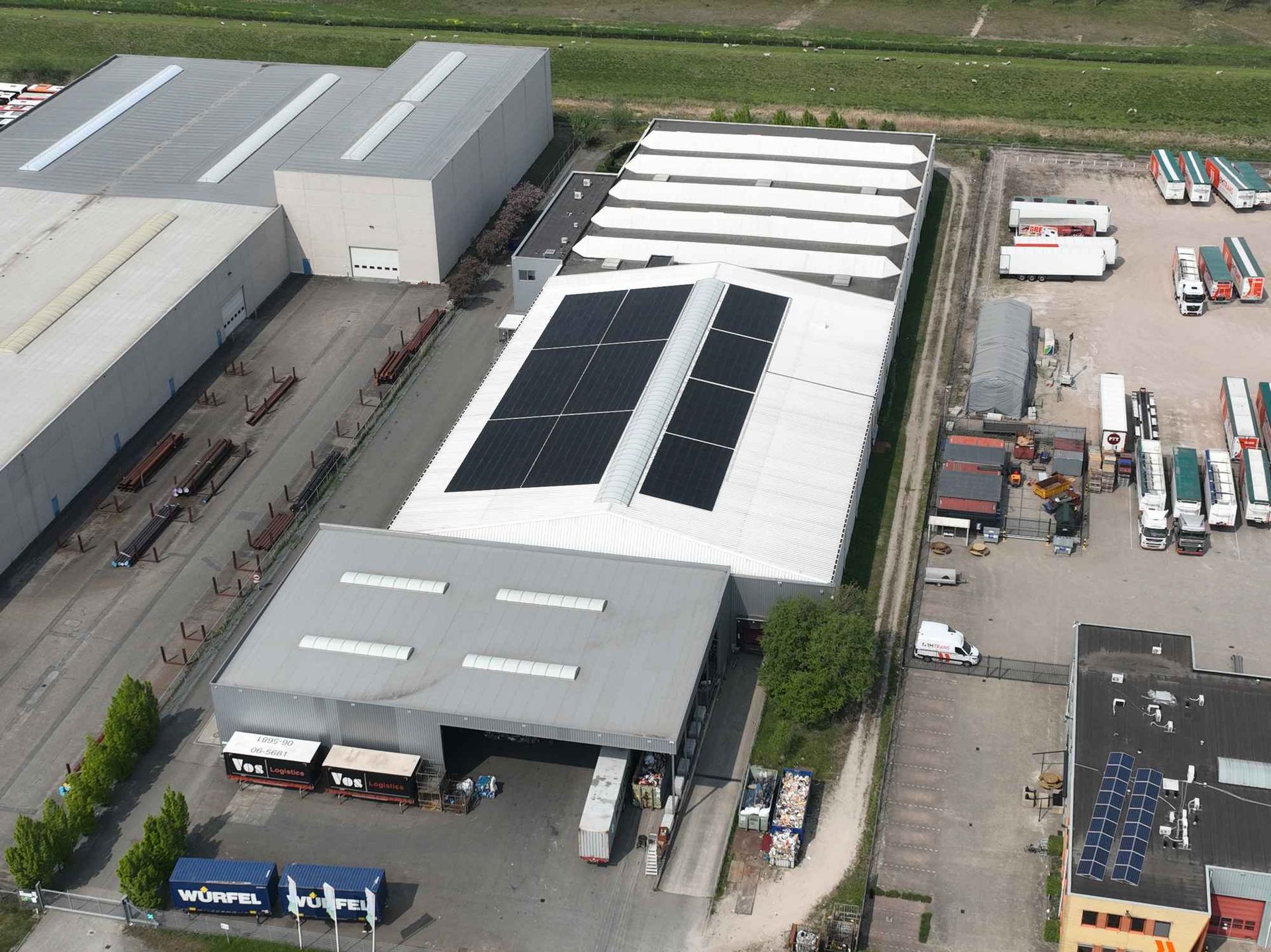Een luchtfoto van een magazijn met zonnepanelen op het dak