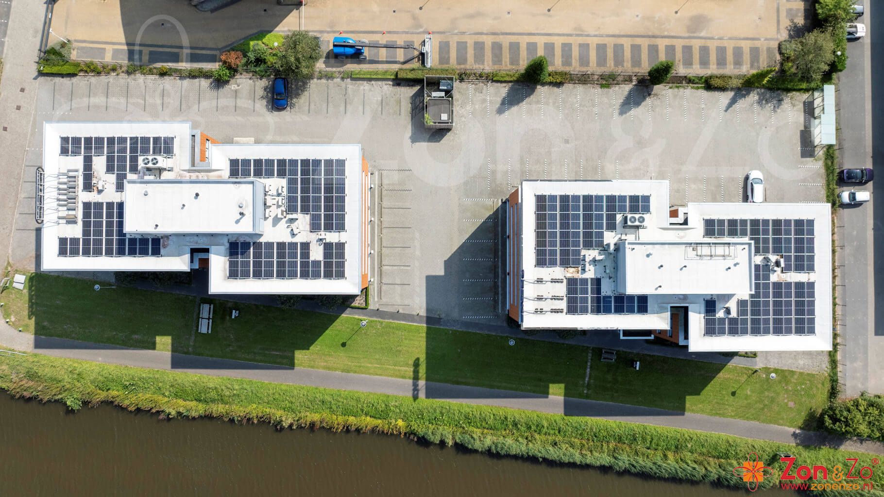Een luchtfoto van twee gebouwen met zonnepanelen op de daken.